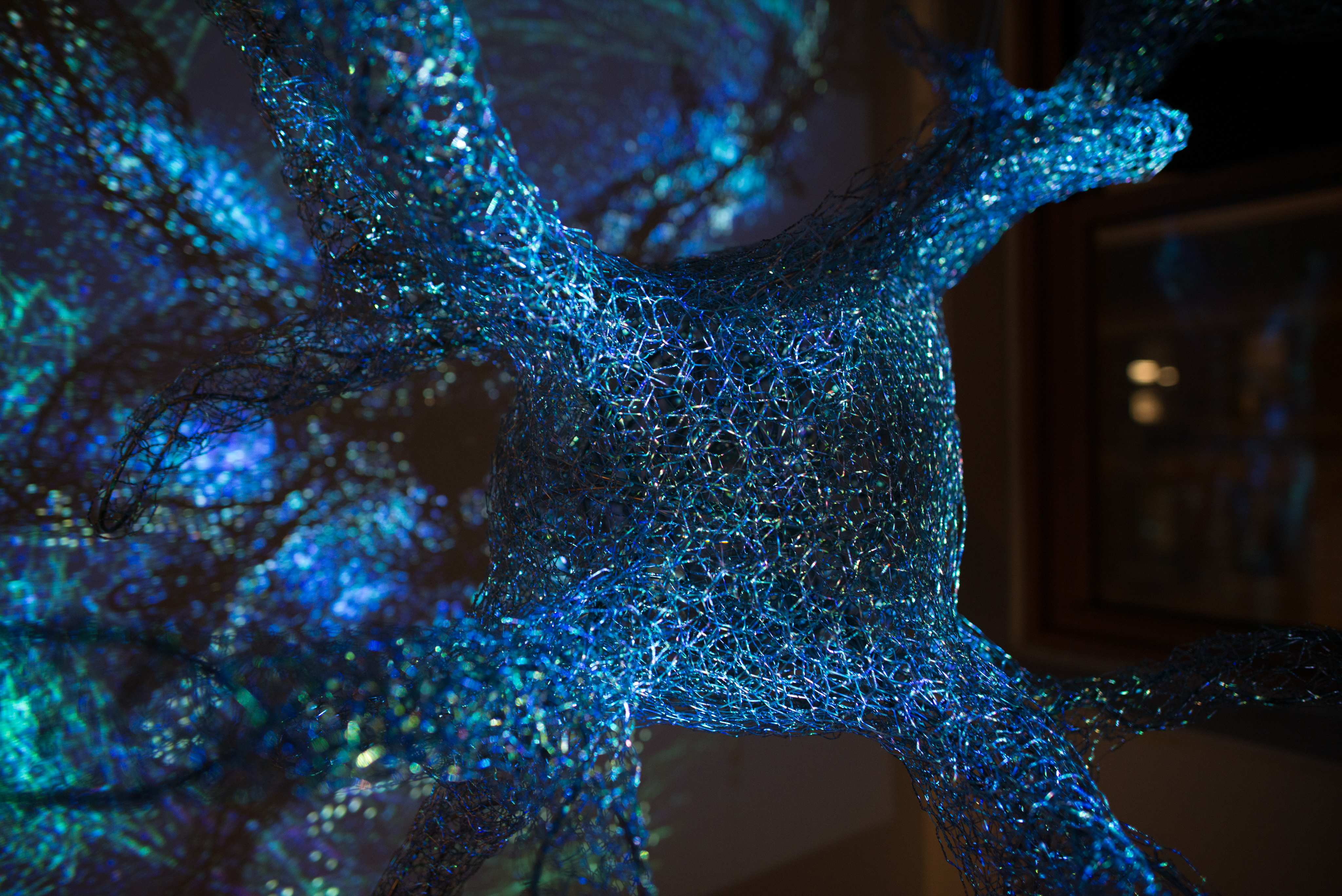 Close up of a giant neuron made of metal wire with light being projected over the surface.