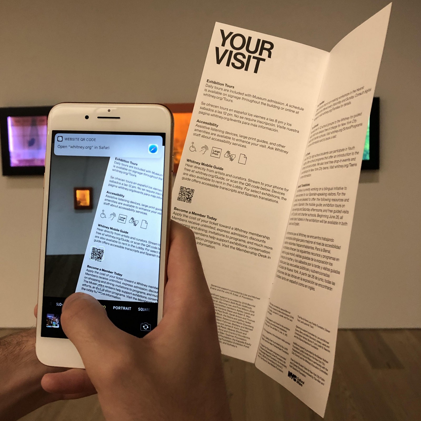 iPhone open to camera scanning a QR code on a paper visitor's guide