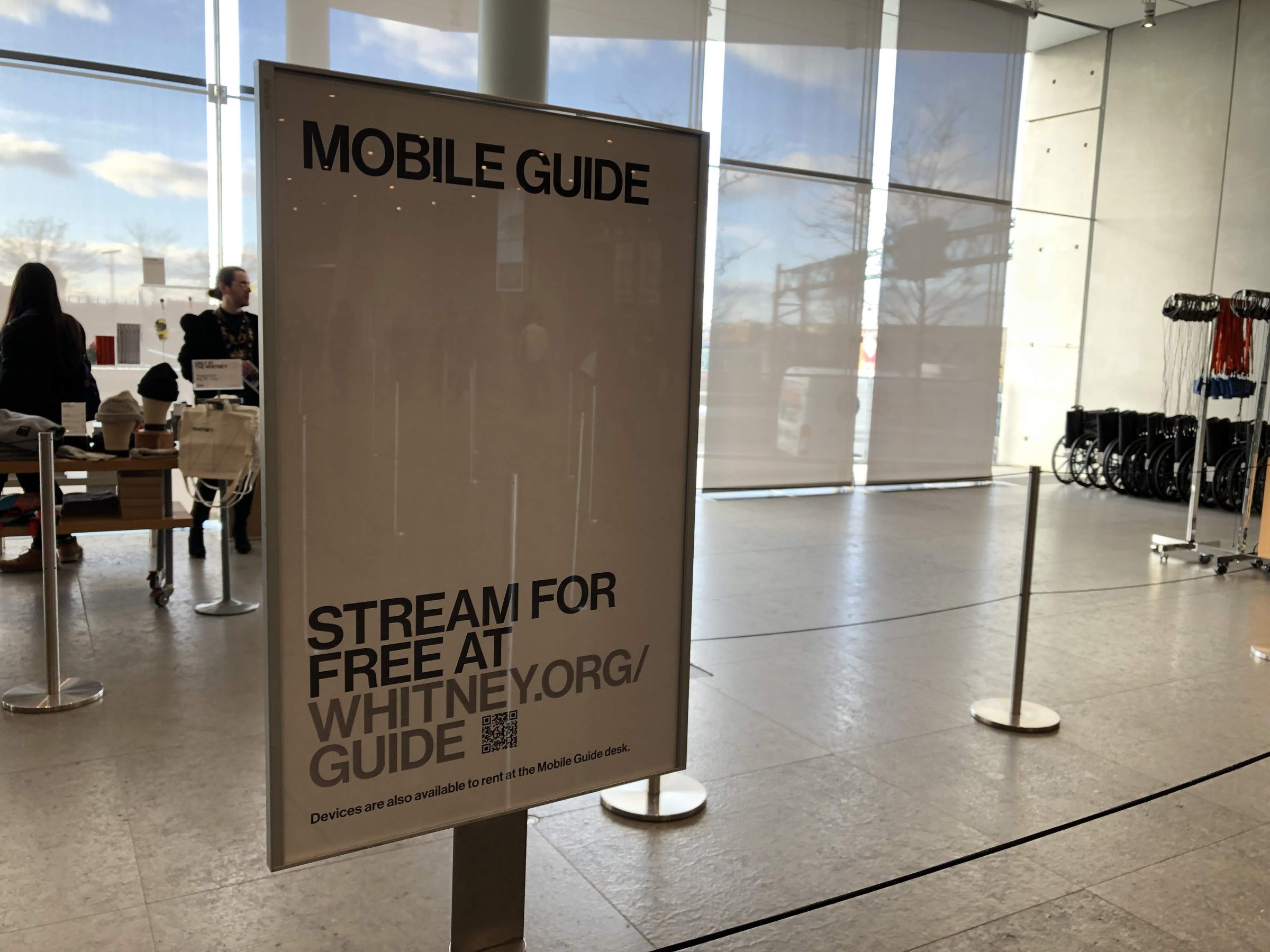 Freestanding stanchion in the museum lobby directing visitors to the Mobile Guide.